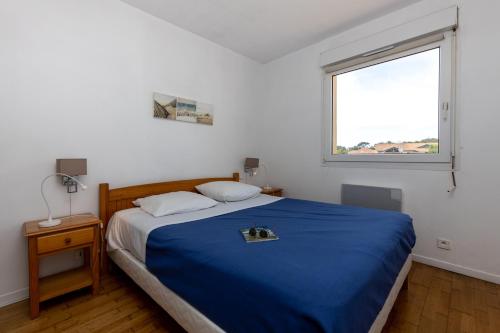 um quarto com uma cama azul e uma janela em Appartement Jean Claude em Moliets-et-Maa