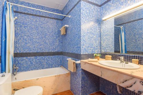 a blue tiled bathroom with a toilet and a sink at Duna Villa, Cala Blanca in Cala Blanca