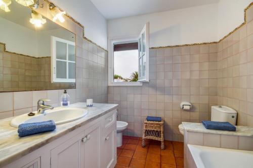 a bathroom with a sink and a toilet and a mirror at Villa Cristina in Cala en Bosc