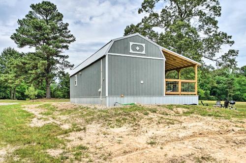 a green barn with a gambrel roof on a field at Broken Bow Cabin on 15 Acres with Stocked Fish Pond! in Broken Bow