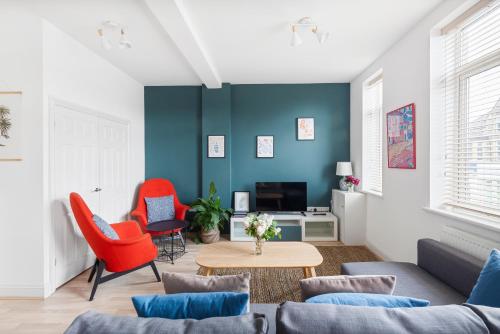a living room with blue walls and red chairs at Albany by Black Door Stays in Cardiff