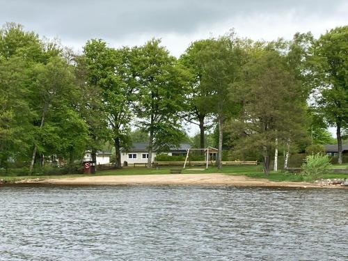 un parque con parque infantil junto al agua en Nice holiday house located by the lake Bolmen, en Ljungby