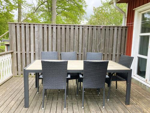 a table and chairs on a deck with a fence at Nice holiday house located by the lake Bolmen in Ljungby