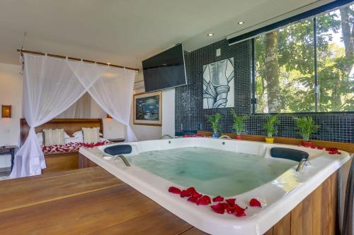 a large bath tub in a room with a bedroom at Guest House Isadora Duncan in Florianópolis