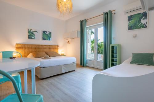 a bedroom with two beds and a table and chairs at Hôtel Almanarre Plage - Hôtel Eco-Responsable face à la mer in Hyères
