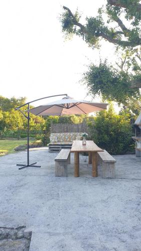 a picnic table with an umbrella and two benches at Quintinha do Periqueiro in Castelo do Neiva