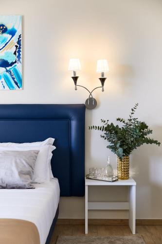 a bed with a blue headboard and a table with a plant at Golden Hotel in Marina di Cecina