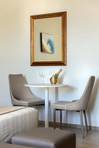 a white table with two chairs and a mirror at Golden Hotel in Marina di Cecina