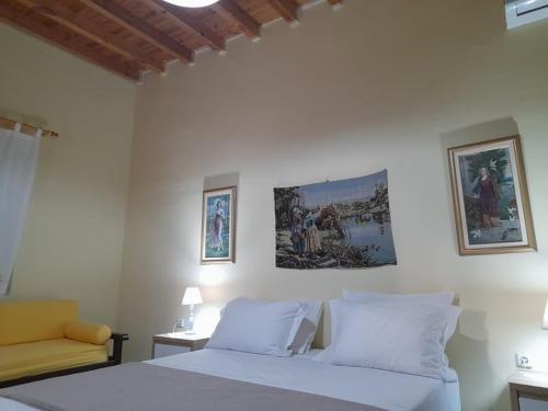 a bedroom with a bed and a chair and pictures on the wall at Mamos Sunset House Plaka in Plaka Milou