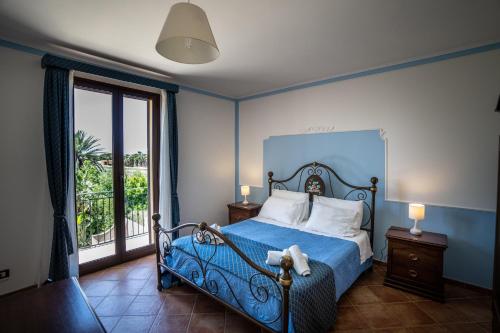 a bedroom with a bed with blue walls and a window at - Vista Egadi - in Torre Nubia