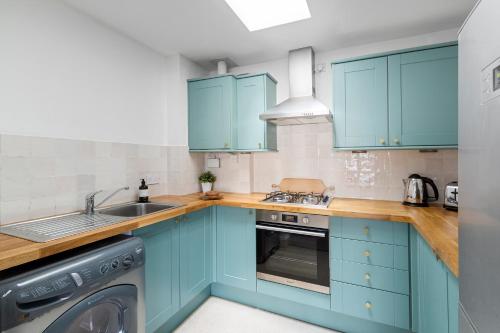 a kitchen with blue cabinets and a dishwasher at Albany by Black Door Stays in Cardiff