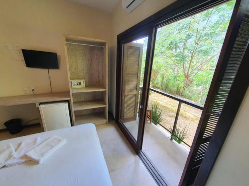 Cette chambre comprend une table blanche et une grande fenêtre. dans l'établissement Hotel Pousada Capão, à Garopaba