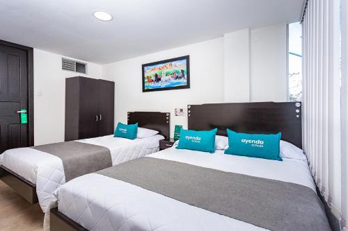 2 camas en una habitación de hotel con almohadas azules en Ayenda Agustin Plaza, en Pasto