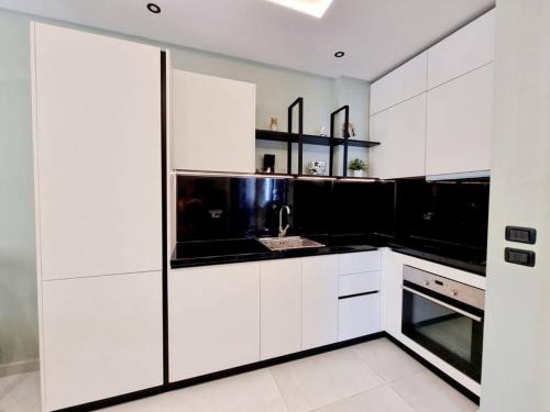 a kitchen with black and white cabinets and a sink at Vacation home near the sea in Durrës