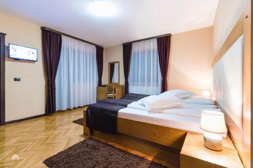 ein Schlafzimmer mit einem großen Bett und einem TV in der Unterkunft White House in Făgăraş