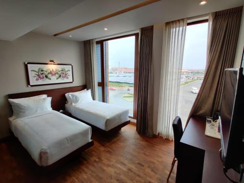 a hotel room with two beds and a large window at Florida Airport Hotel Kochi in Nedumbassery