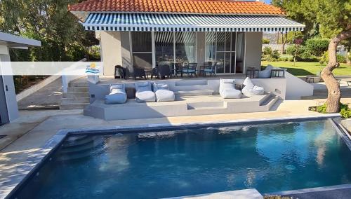 a swimming pool in front of a house at Villa PortoMare in Porto Rafti