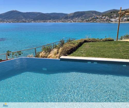 a large blue swimming pool with a view of the water at Villa PortoMare in Porto Rafti