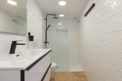 een witte badkamer met een douche en een wastafel bij Precioso apartamento con patio y dos habitaciones en el barrio de Picasso in Málaga