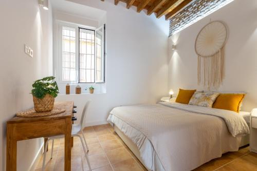 een witte slaapkamer met een bed en een tafel bij Precioso apartamento con patio y dos habitaciones en el barrio de Picasso in Málaga