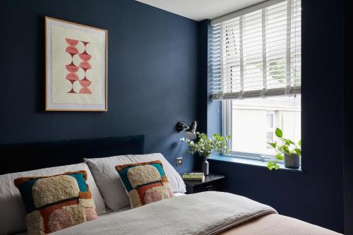a bedroom with blue walls and a bed with pillows at Pontcanna by Black Door Stays in Cardiff