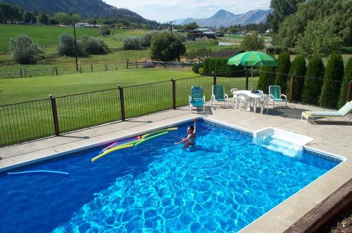 a boy is playing in a swimming pool at Kamloops Log Home Bed and Breakfast in Kamloops