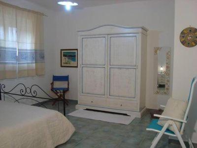 a bedroom with a bed and a chair and a cabinet at Le Pavoncelle Blu in Cala Gonone