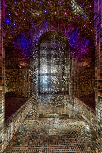 an empty room with a tiled wall with purple lights at Sofijos Rezidencija in Birštonas