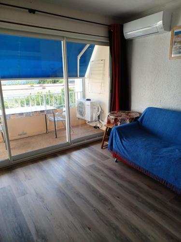 a bedroom with a blue bed and a large window at Juste à côté de la plage, wifi in Port-la-Nouvelle