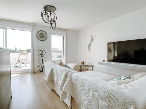 Cette chambre blanche dispose de 3 lits et d'une télévision. dans l'établissement Appartement type industriel dans cadre provençal, à Sanary-sur-Mer