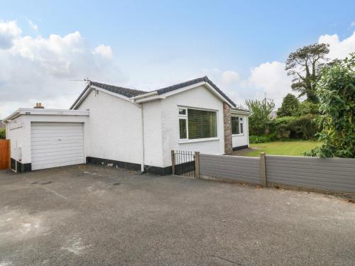 a white house with a fence in front of it at H Jem in Benllech