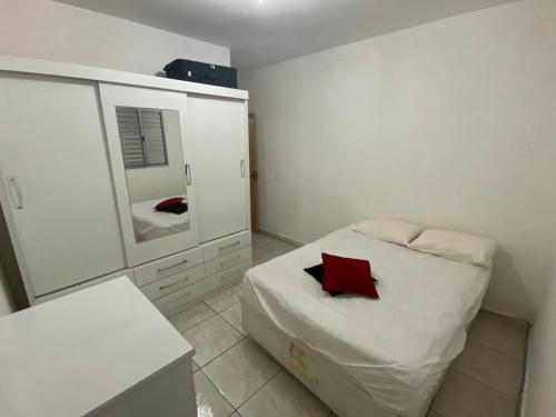 een kleine slaapkamer met een bed en een spiegel bij Lar Doce mar in Mongaguá