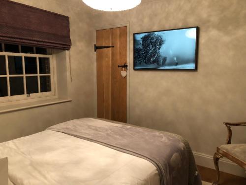 a bedroom with a tv hanging on the wall at Glanthams Lodge Guestroom in Shenfield