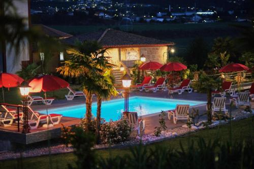 a swimming pool with chairs and umbrellas at night at Aldeia da Quinta do Paço - Turismo rural Santo Tirso in Santo Tirso