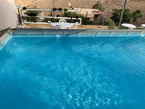 a large blue swimming pool with two white chairs at Tamar's House in Arad