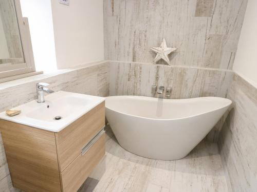 a white bathroom with a sink and a bath tub at A Mor in Llanfairpwllgwyngyll