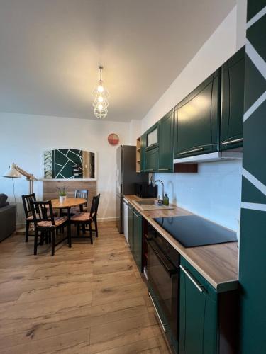 a kitchen with green cabinets and a dining table at Apartament Poznańska in Suwałki