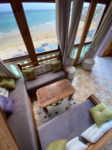 a living room with a couch and a table and the beach at Single fin beach house in Taghazout