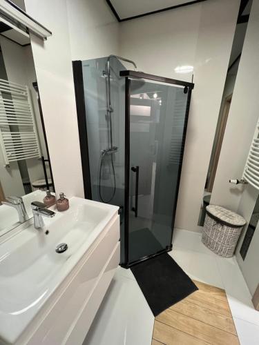 uma casa de banho com uma cabina de duche em vidro e um lavatório. em Apartament Poznańska em Suwałki