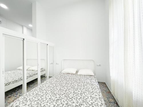 Habitación blanca con 2 camas y espejo. en Precioso loft en el corazón de triana, en Sevilla