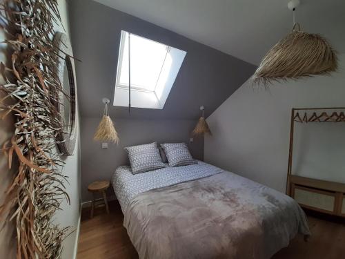 een slaapkamer met een bed en een dakraam bij Le Cottage du Bois Flotté in Saint-Malo