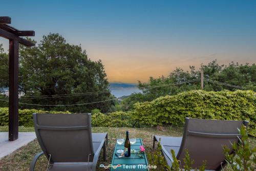 two chairs and a table with a bottle of wine at Villa Ca Damare, TerreMarine in Le Grazie