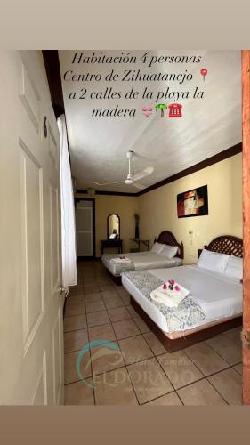 two beds in a room with a sign on the ceiling at Hotel Familiar El Dorado in Zihuatanejo