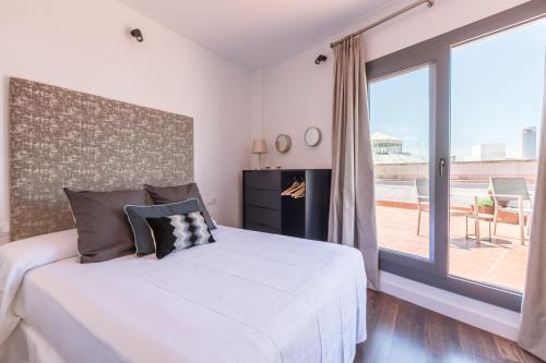 a bedroom with a white bed and a large window at Green-Apartments Sierpes Luxury Suites in Seville