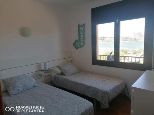Habitación pequeña con 2 camas y ventana en Riells playa en L'Escala