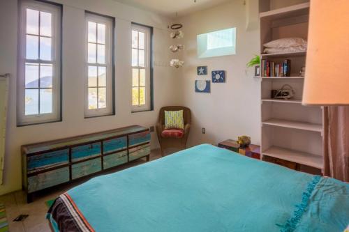 a bedroom with a bed and a chair and windows at Tortola Adventure Private Villa Ocean-View Pool in Freshwater Pond