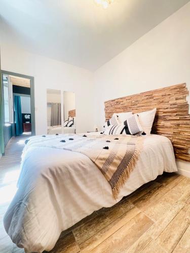 une chambre avec un grand lit avec une tête de lit en bois dans l'établissement Chez-YU, à Carcassonne