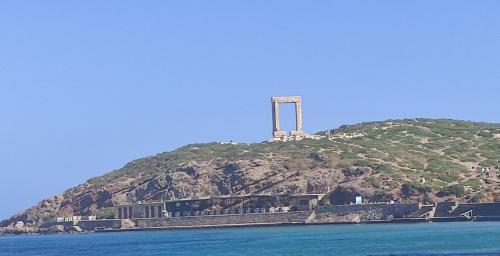 a hill with a monument on top of it on the water at Votsalo Beach House in Moutsouna Naxos