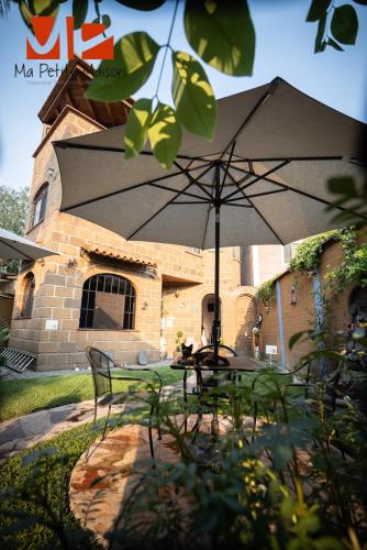 a table with an umbrella in front of a building at Ma Petite Maison in Tepoztlán