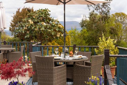 an outdoor table with an umbrella on a deck at Duisdale House Hotel in Isleornsay